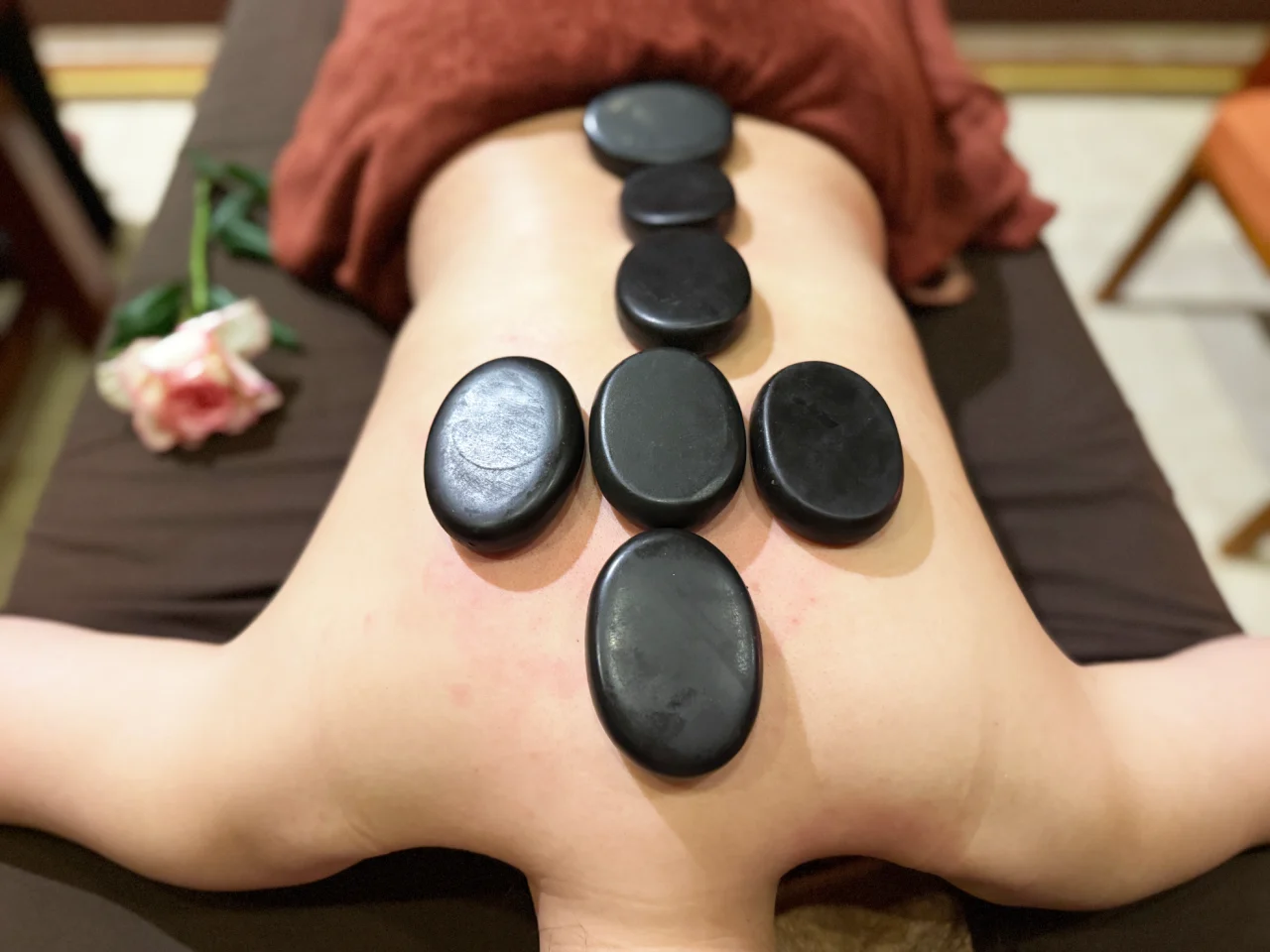 Hot stones placed on a client's back during a hot stone massage at Rosie's Magical Spa.